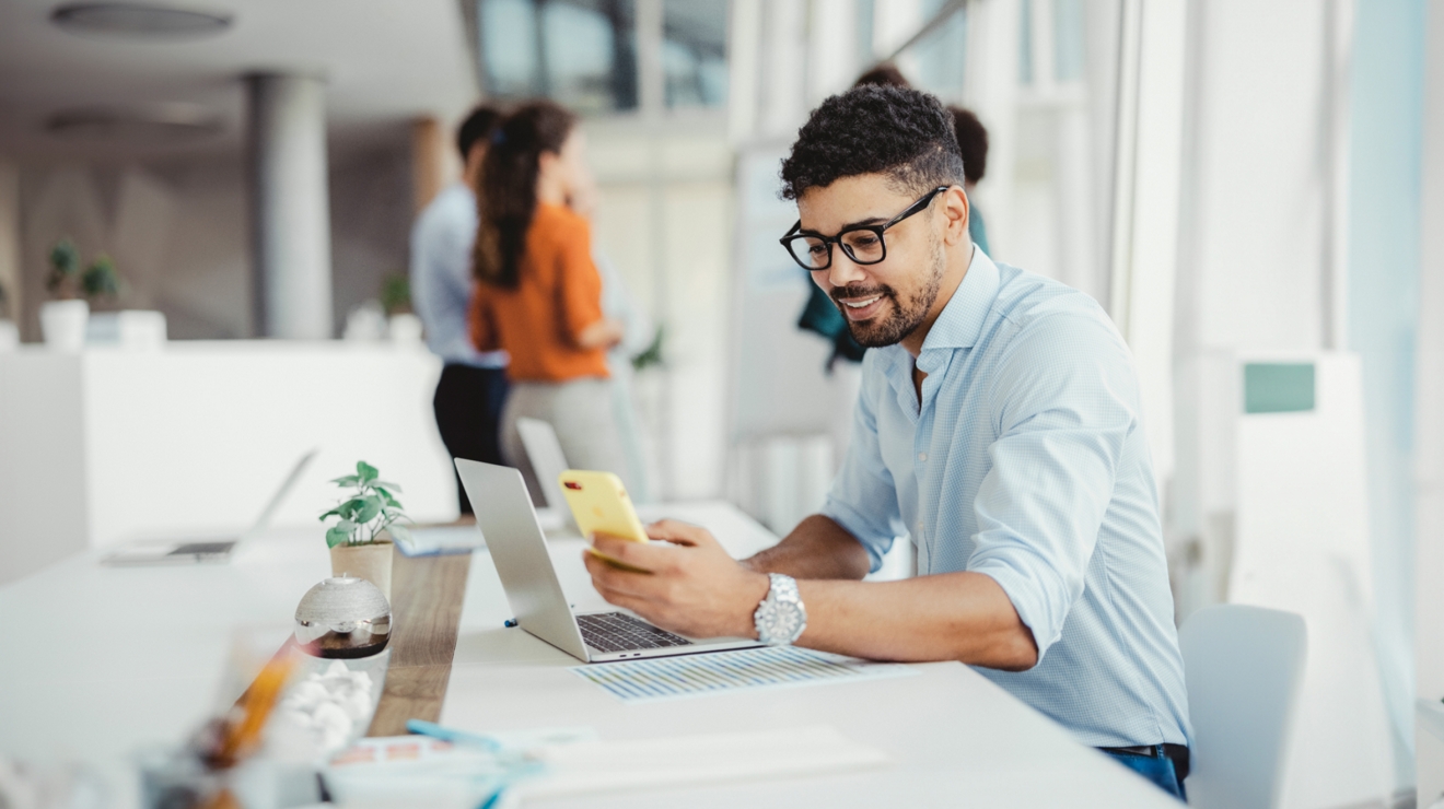 Un empleado revisa su celular mientras trabaja en la oficina.