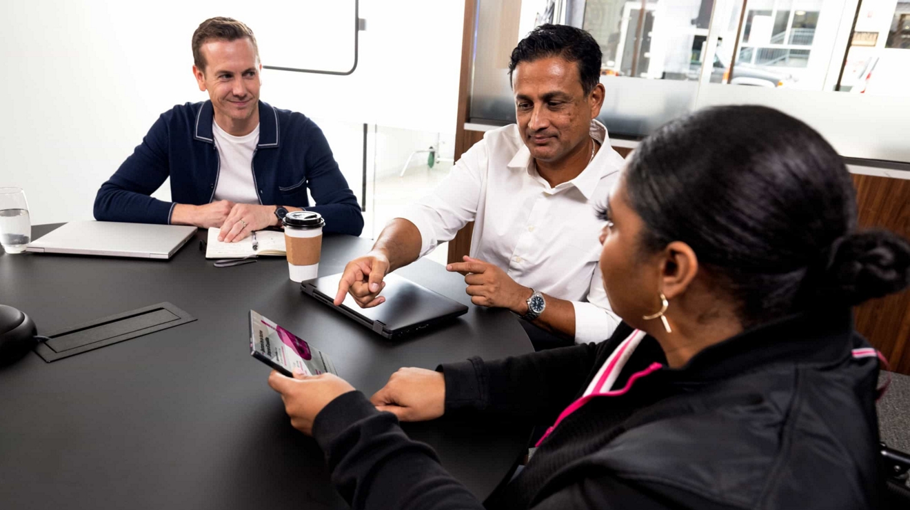 Un grupo de empleados gubernamentales en una sala de reuniones discuten información que ven en una tablet.