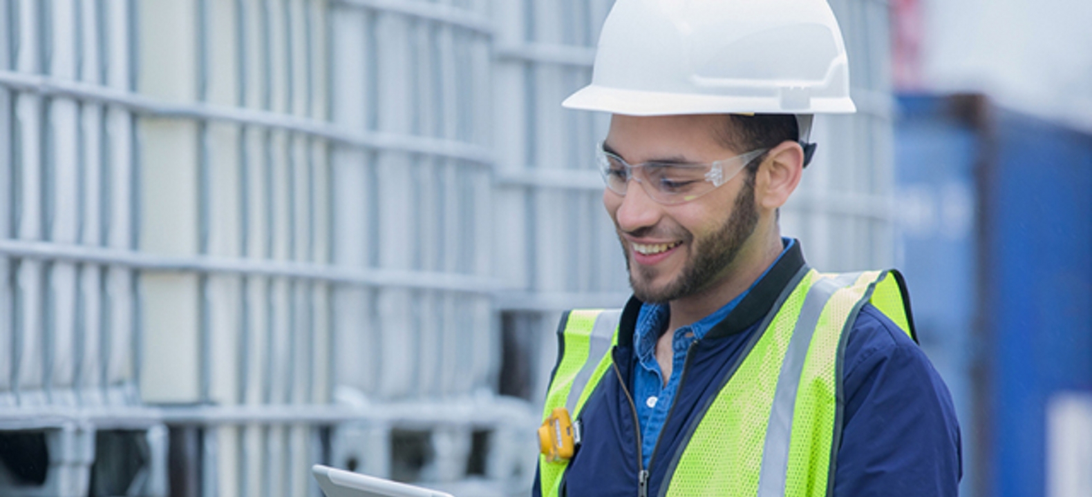 Un ingeniero sonriente usando una tablet para comprobar un cargamento de productos químicos en un oleoducto.