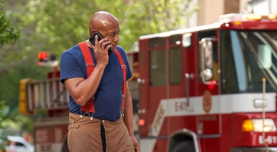 Un bombero habla por teléfono frente a un camión de bomberos en un lugar de respuesta.