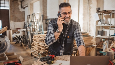 Un carpintero habla por su smartphone en su taller.