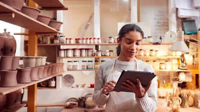 Una alfarera en un taller de cerámica revisa los pedidos con su tablet digital.