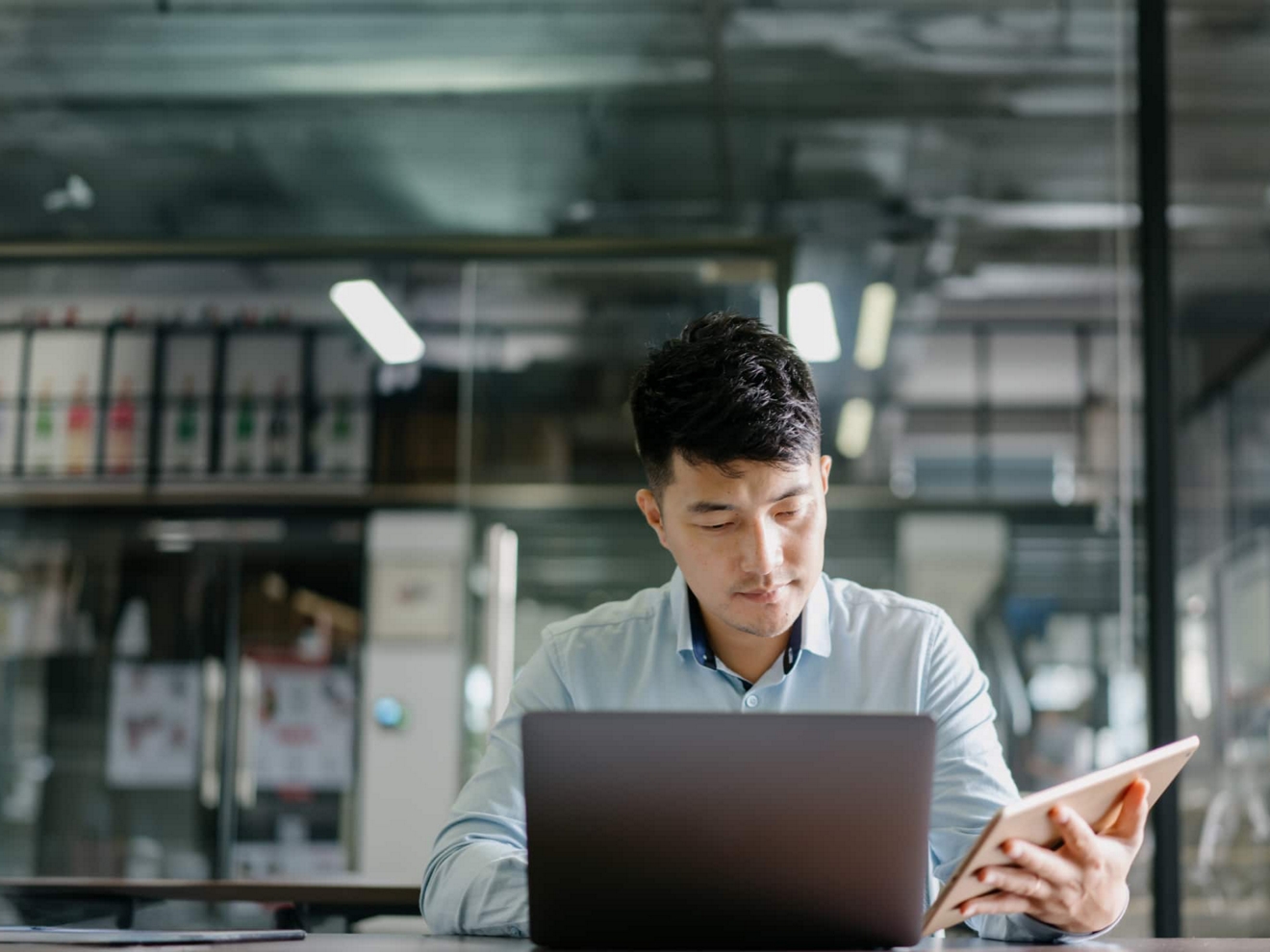 Un profesional de negocios trabaja de forma segura con su laptop y tablet en un escritorio.
