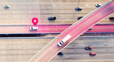 Vista aérea de una autopista con líneas magenta e ícono de ubicación.
