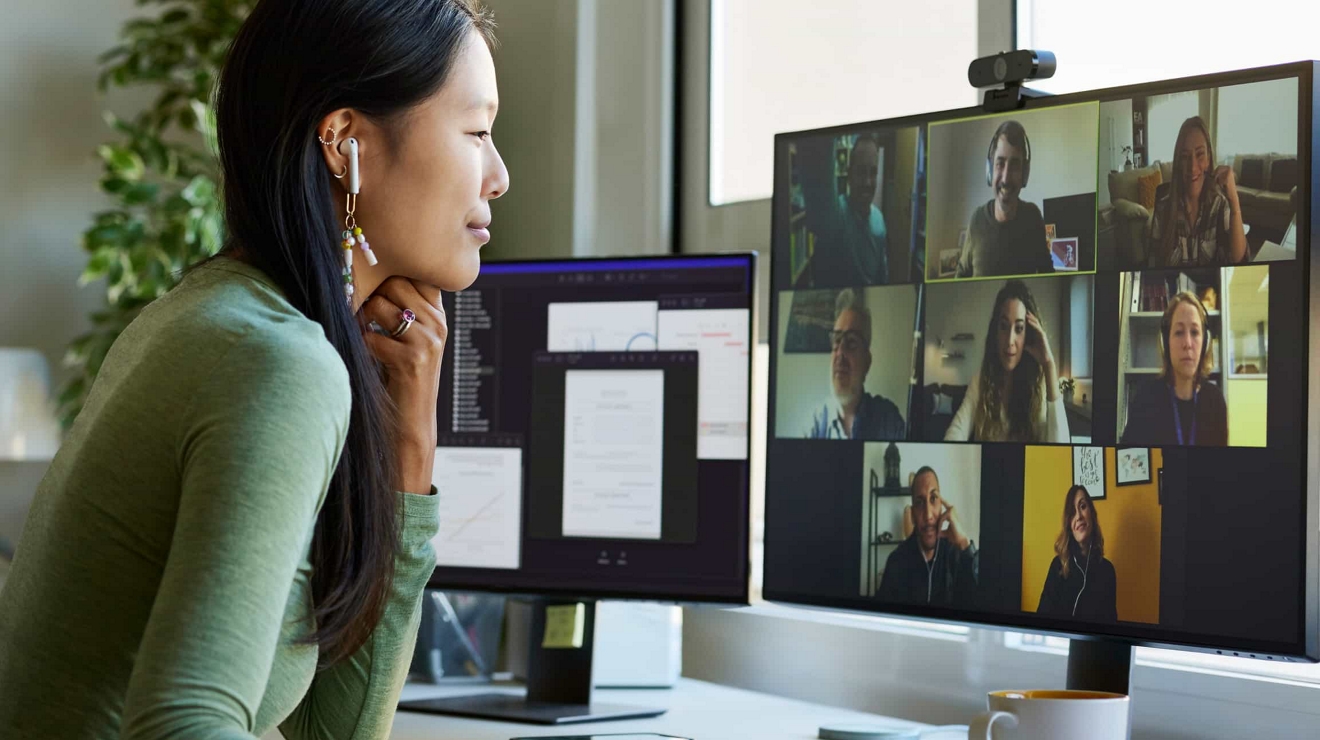 Un empleado utiliza dos monitores para atender una videollamada y acceder a diferentes documentos.