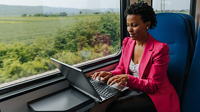 Joven profesional disfruta de la conectividad 5G mientras trabaja con su laptop desde el tren.