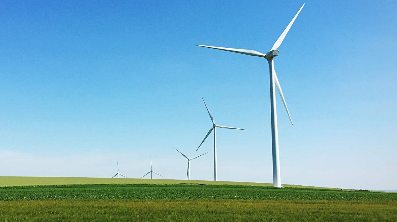 Una hilera de molinos de viento en línea a través de un gran campo agrícola.