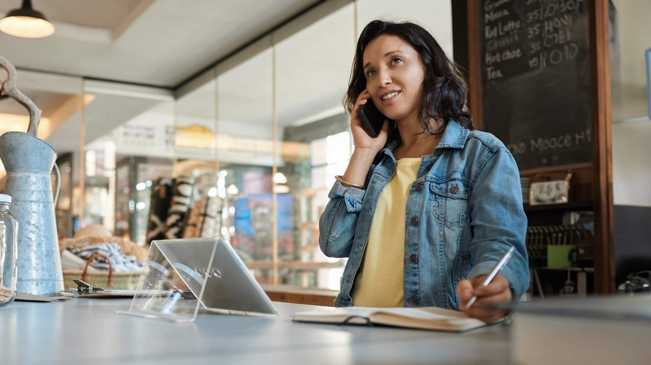 La gerente de una cafetería habla por teléfono y toma notas.