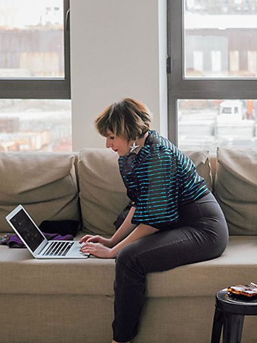 Mujer sentada en su sofá trabajando en una laptop