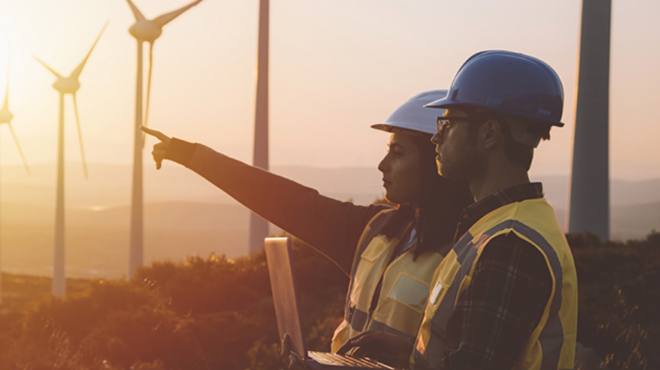 Dos trabajadores mirando un campo de aerogeneradores