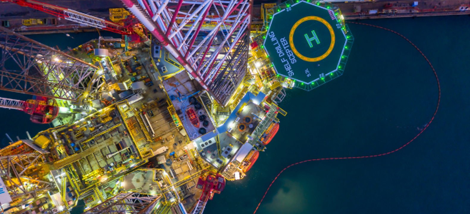 Vista aérea de una plataforma petrolífera en altamar por la noche.