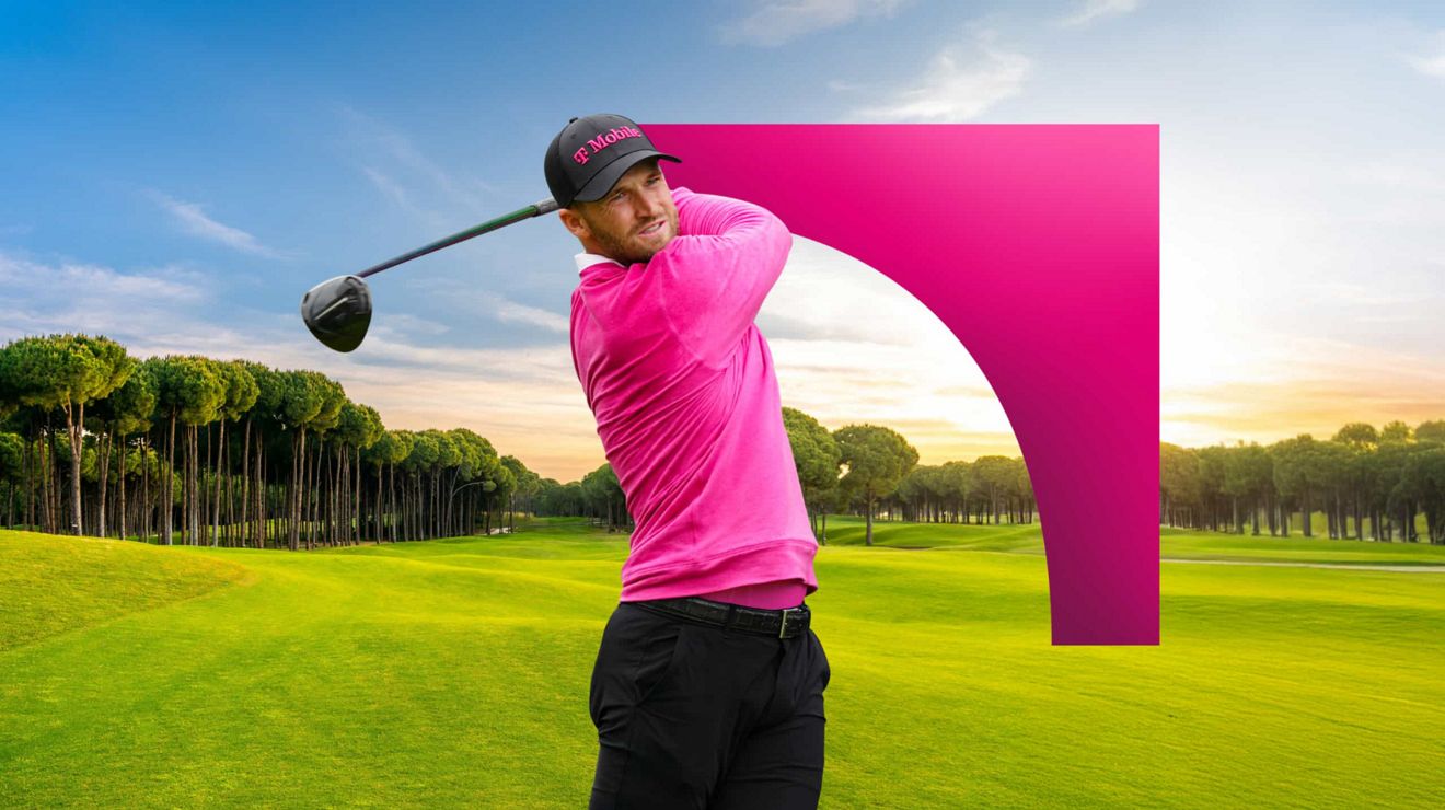 Un golfista de la PGA con gorra y camiseta de T-Mobile termina un swing y sigue la bola mientras cae.