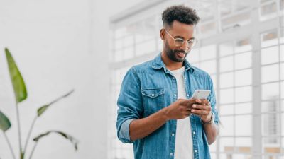 Un profesional consulta su smartphone en una oficina moderna y luminosa.