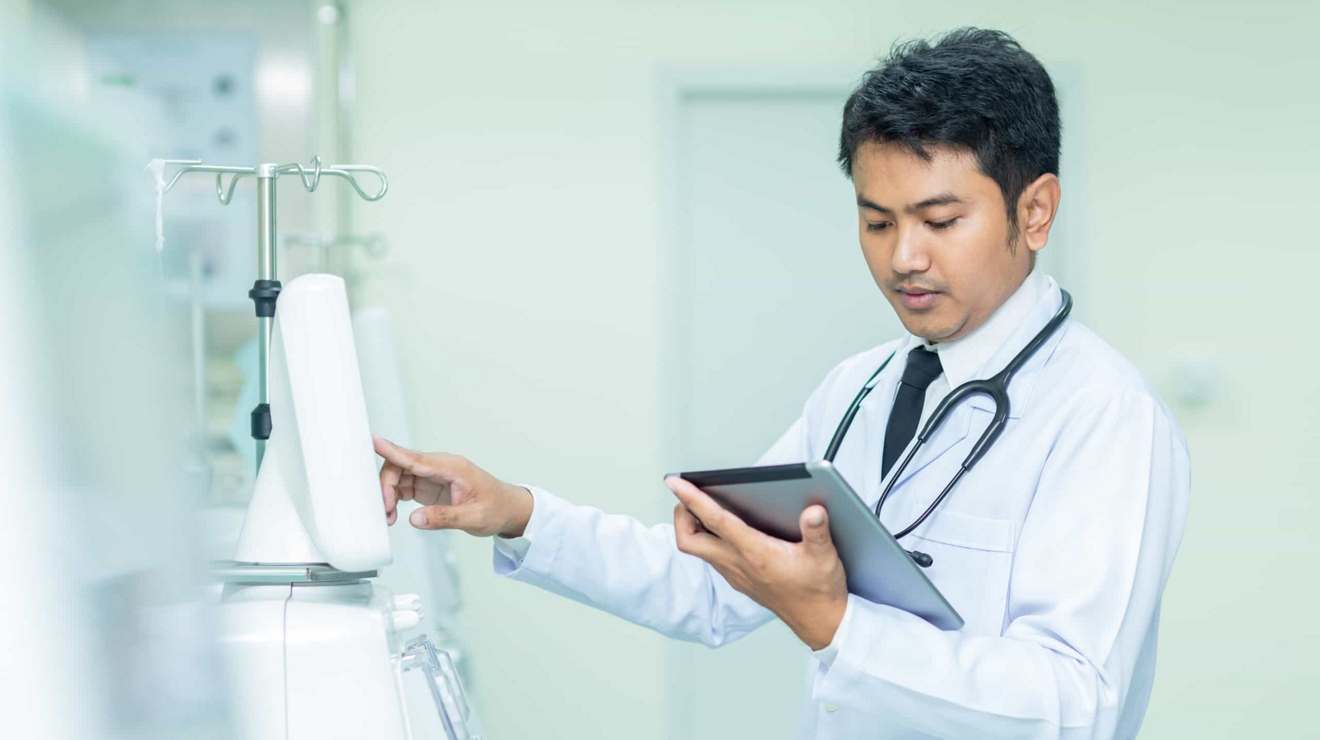 Un médico toca un dispositivo médico y revisa la información en una tablet.