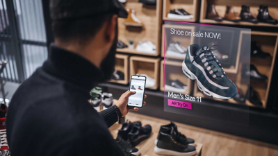 Un comprador de zapatos consulta el sitio web del minorista en su smartphone mientras compra en la tienda.