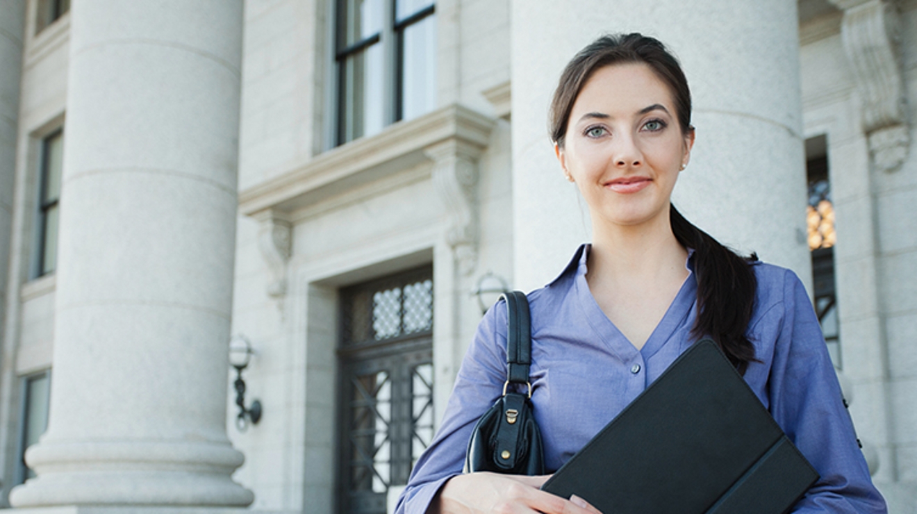 Un empleado del gobierno se encuentra afuera de un edificio gubernamental sosteniendo una tablet conectada.