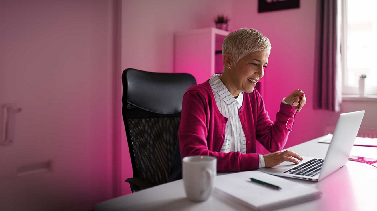 Empleada de una pequeña empresa con un suéter magenta trabaja con confianza en su laptop conectada a 5G.