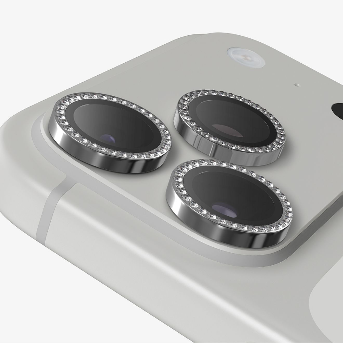 Primer plano de tres protectores para lentes de cámara ZAGG Glass Elite de color plateado con detalles de diamante, bien fijados sobre los lentes de la cámara trasera de un iPhone Pro color plata.