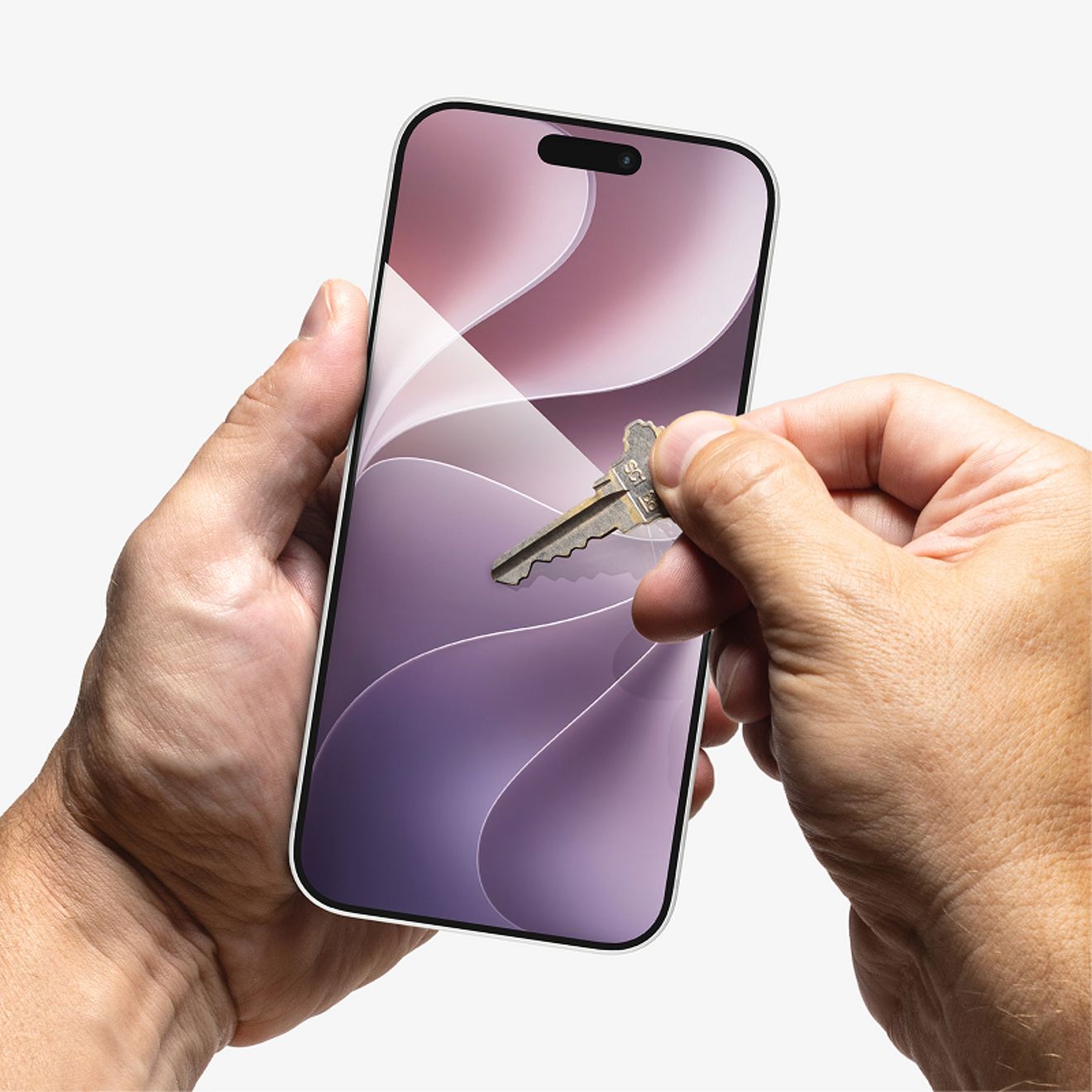 Una mano sostiene un iPhone mientras se presiona una llave de metal contra la pantalla protegida por el vidrio templado ZAGG XTR4, lo que demuestra su resistencia a los rayones.