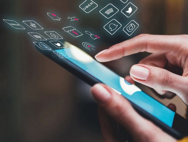Primer plano de una mano tocando un smartphone con íconos de apps girando a su alrededor