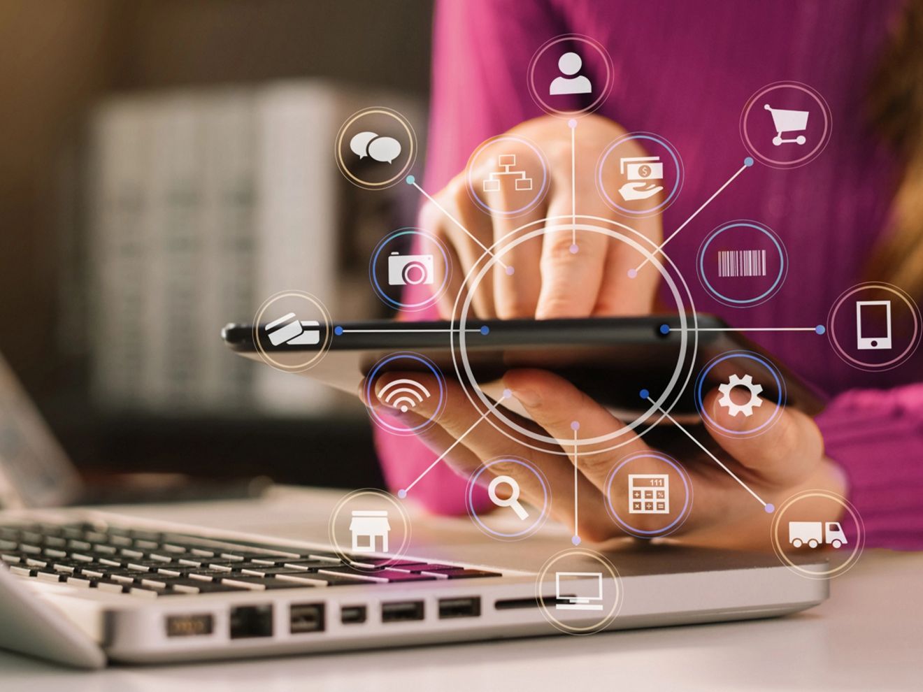 Una persona está usando un smartphone junto a una laptop, con íconos de conexión sobre el smartphone.