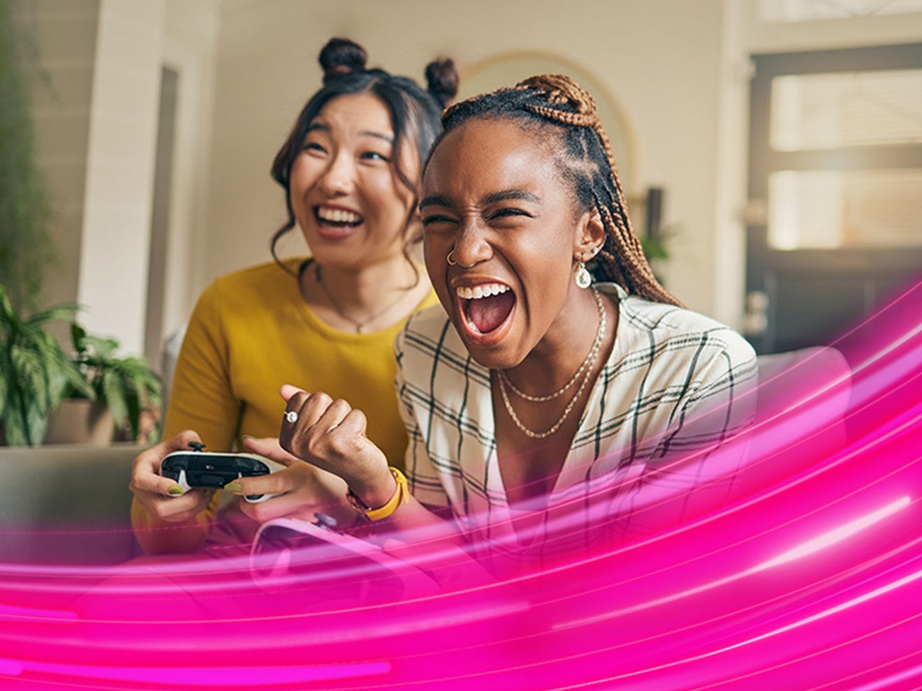 Dos mujeres están sentadas en un sofá jugando videojuegos.