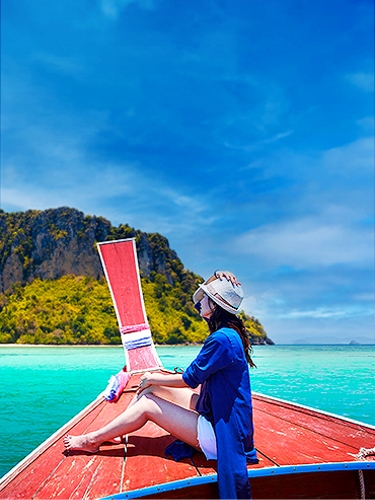 Una mujer en un barco mirando una isla que está delante de ella.