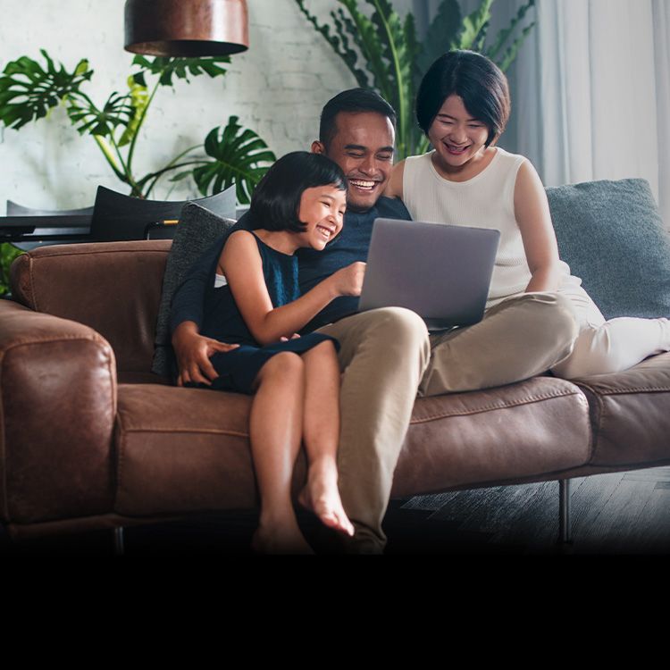 Una familia sentada en un sofá comparte una laptop.