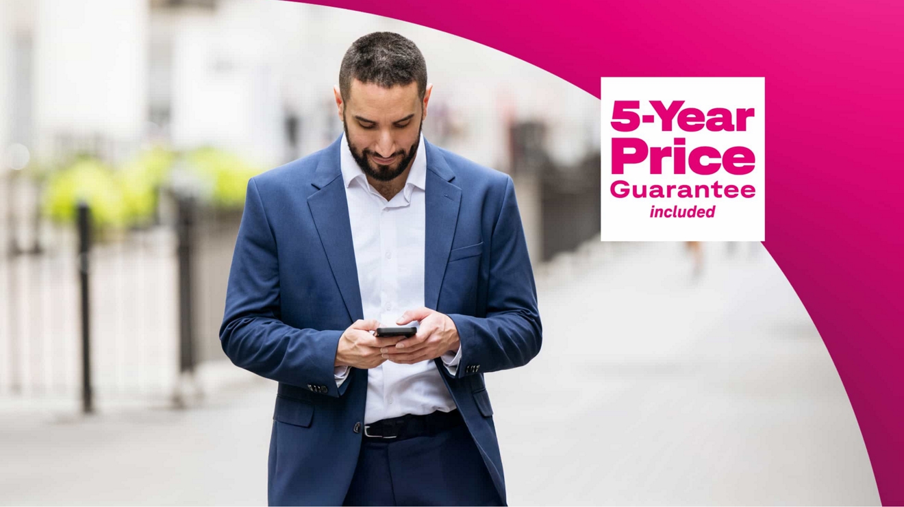 Texto de Precio garantizado por 5 años foto de un empresario en una acera enviando un mensaje con su teléfono.