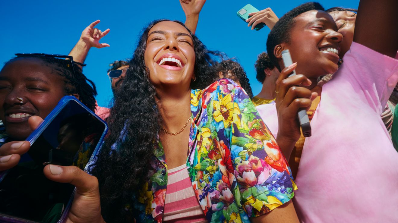 Amigos celebrando al aire libre mientras usan sus teléfonos.
