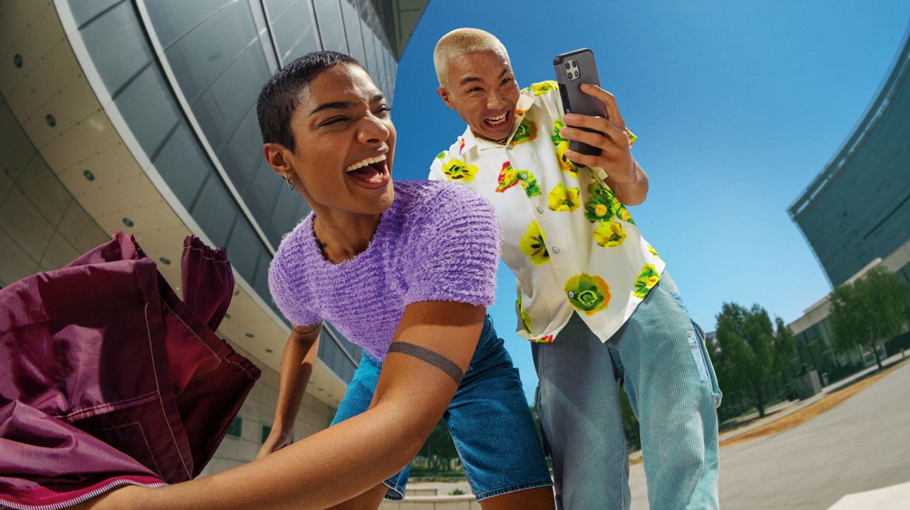 Grupo de amigos sonriendo y tomando un selfie al aire libre con un smartphone.