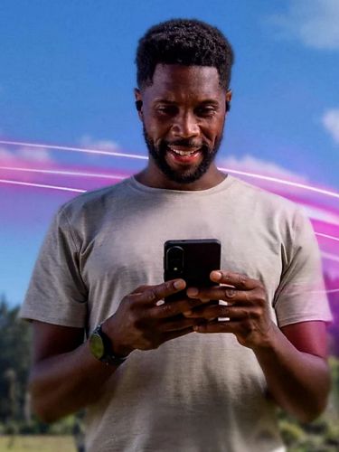 Un hombre mira su smartphone al aire libre, en un entorno natural.