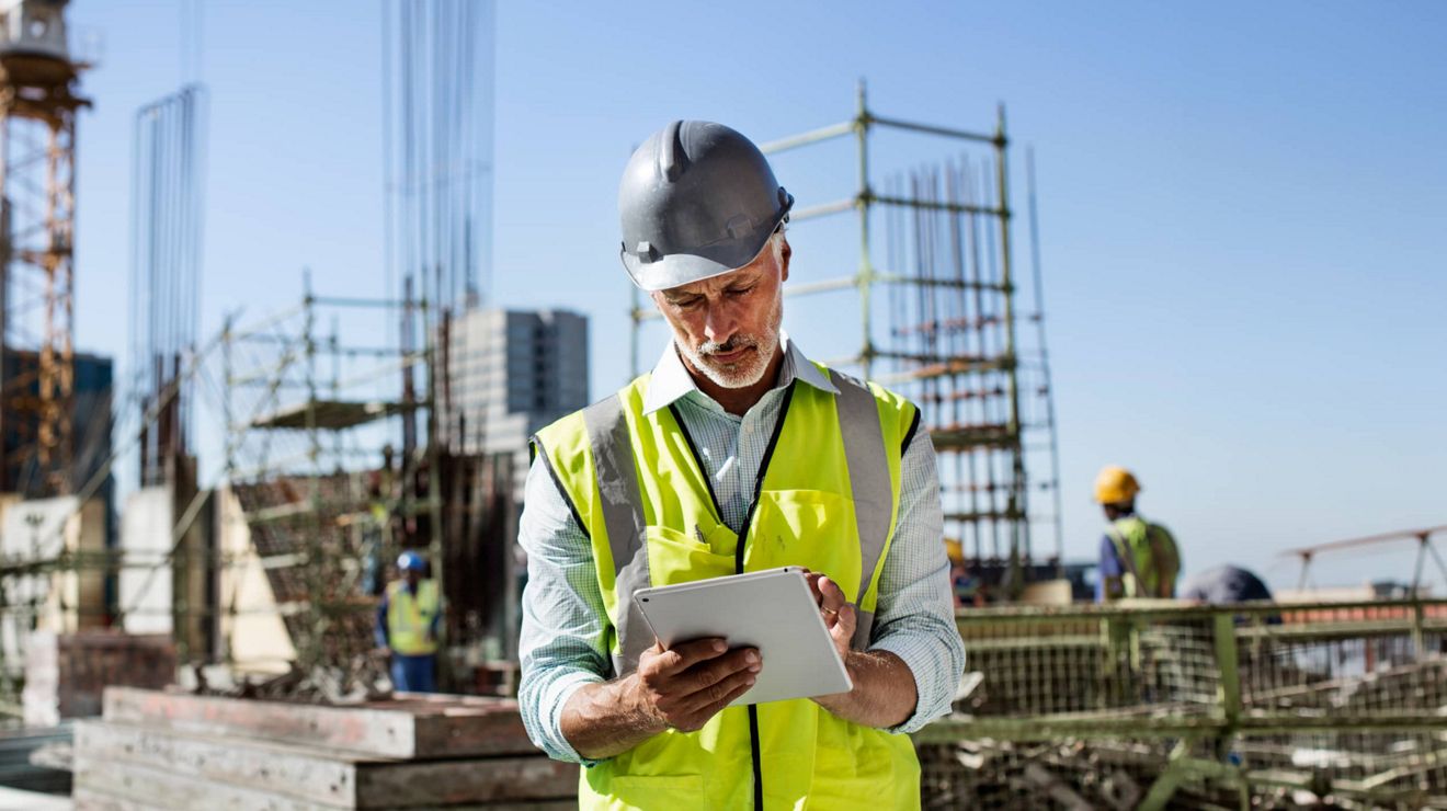 Un trabajador de la construcción en una obra gestiona las operaciones desde una tablet mediante conectividad prioritaria.