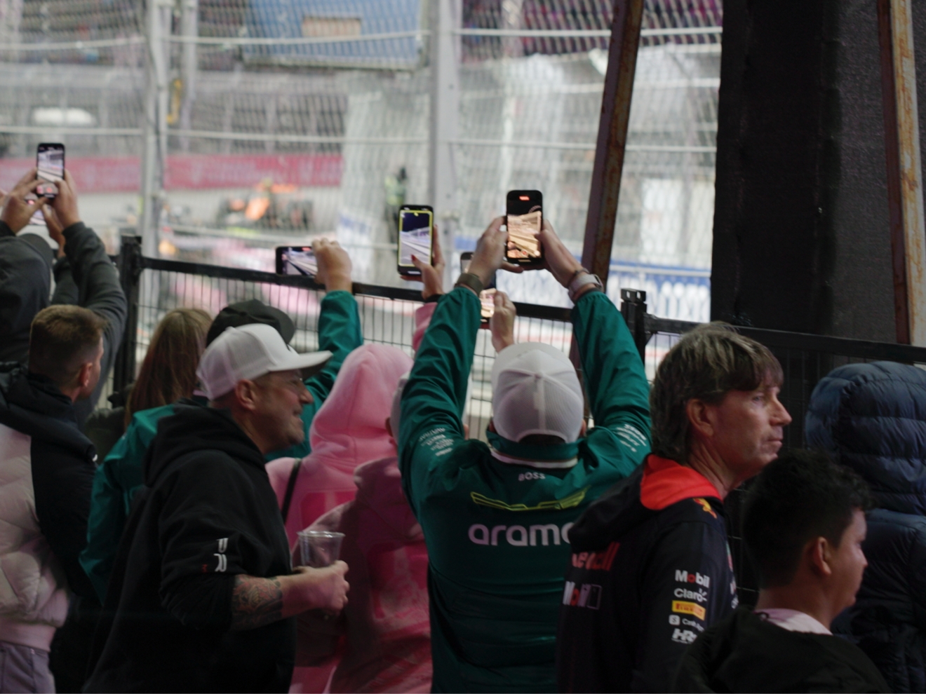 Varias personas entre la multitud tomando fotos de la carrera con sus teléfonos.