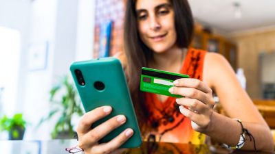 Mujer usa tarjeta de crédito para hacer una compra en su teléfono.