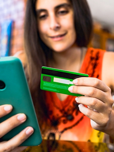 Mujer usa tarjeta de crédito para hacer una compra en su teléfono.