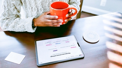 Cliente sentado a un escritorio con una taza de café y una tablet.