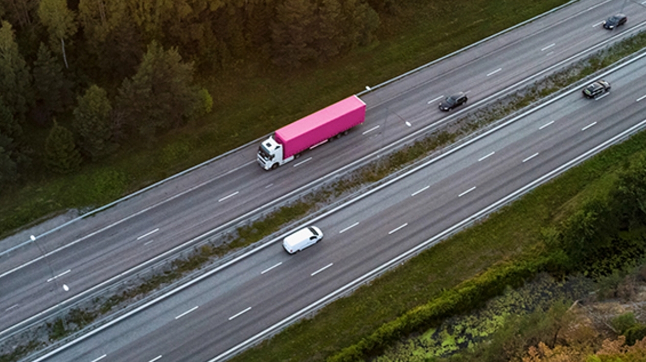 Camión semirremolque magenta en la autopista.