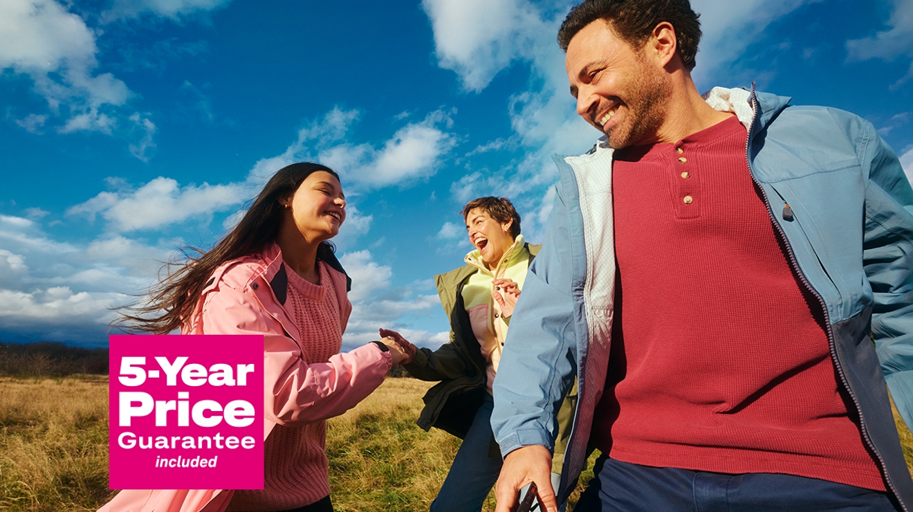 En un campo abierto, dos mujeres y un hombre ríen junto a las palabras "precio garantizado por cinco años".