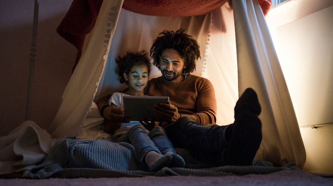 Un hombre y una niña sonríen mientras miran una tablet.