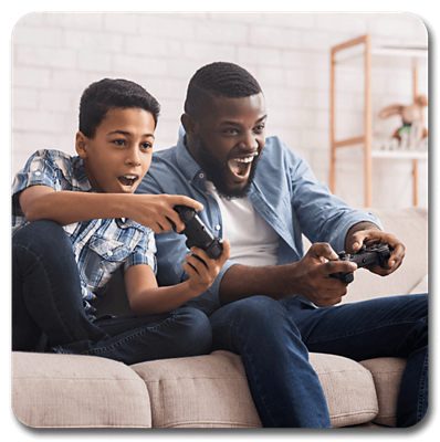 Padre e hijo sentados en el sofá de la sala de estar mientras juegan a videojuegos.