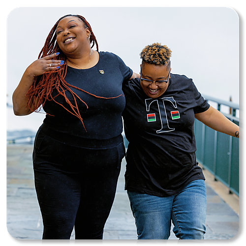 Dos mujeres negras riendo y paradas una junto a la otra.