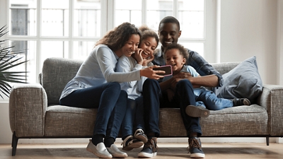 Familia sentada en el sofá reunida alrededor de un smartphone