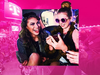 Dos mujeres sentadas en un auto, riendo y mirando sus teléfonos.