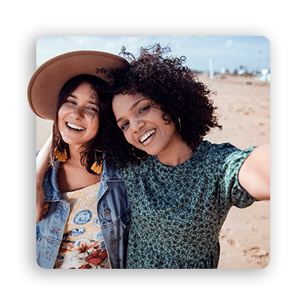 Dos mujeres en una playa, sonriendo mientras se toman un selfie