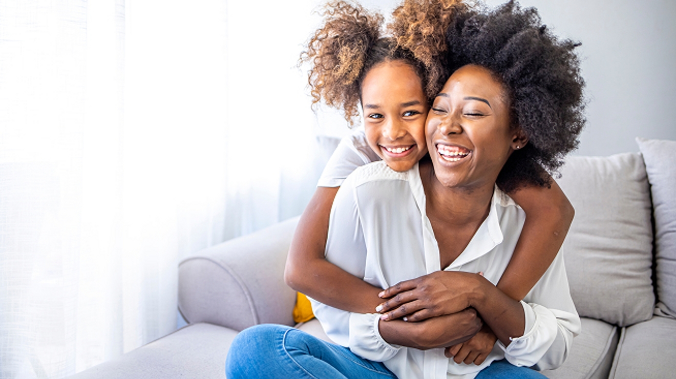 En una sala de estar, una niña pequeña abraza a su madre.