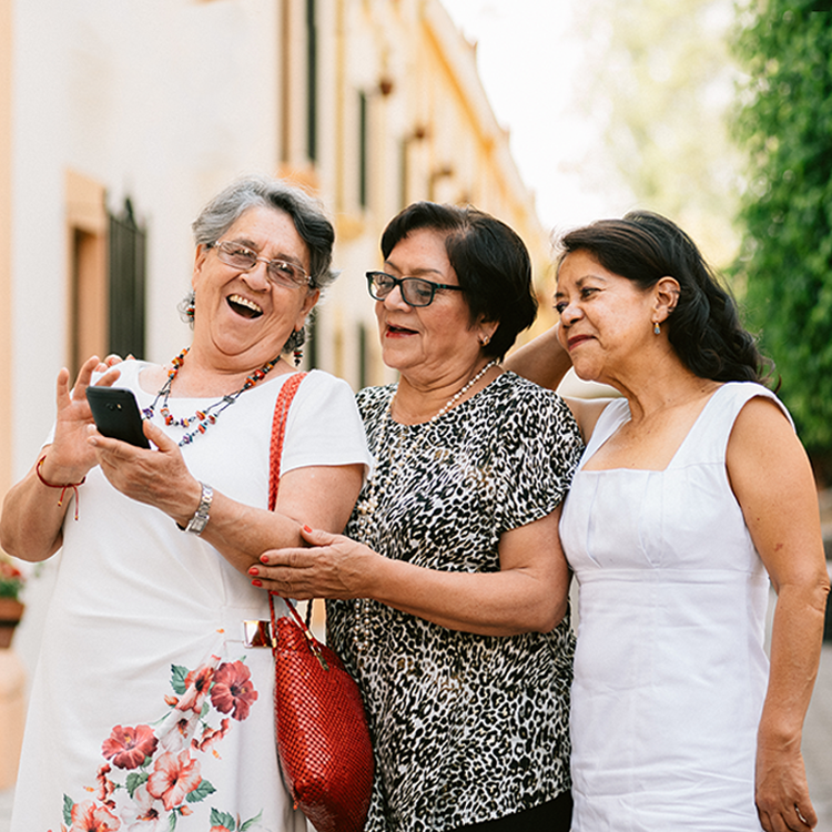 Tres señoras mayores que se ríen mientras miran un teléfono