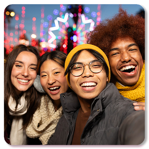 Cuatro estudiantes se toman un selfie con un colorido fondo de carnaval.
