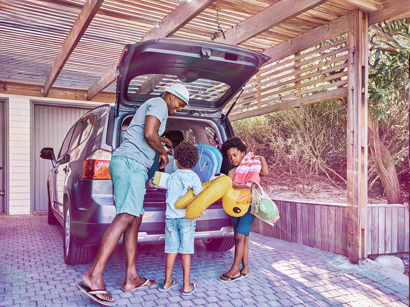 Una familia cargando el maletero de su auto para irse de vacaciones.