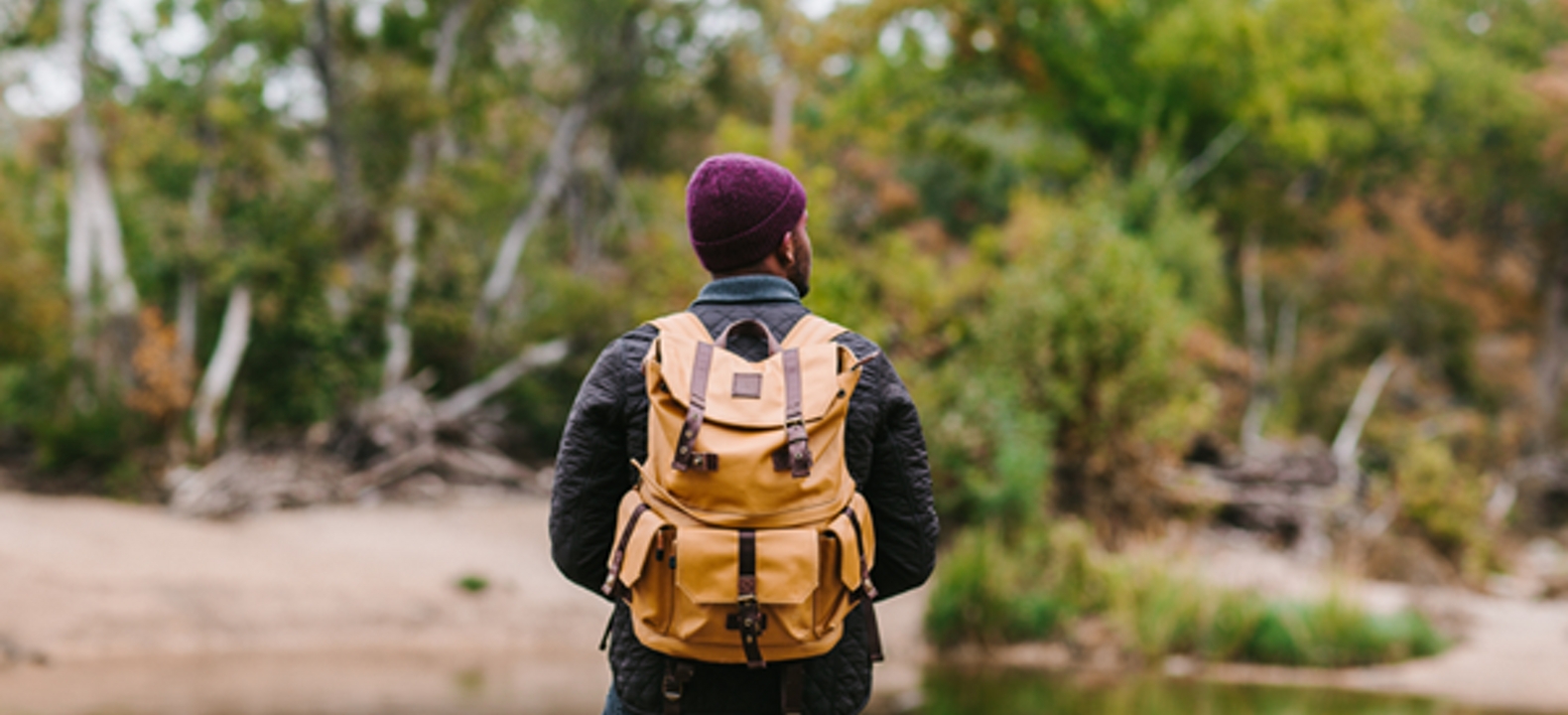 Hombre con mochila mirando un estanque